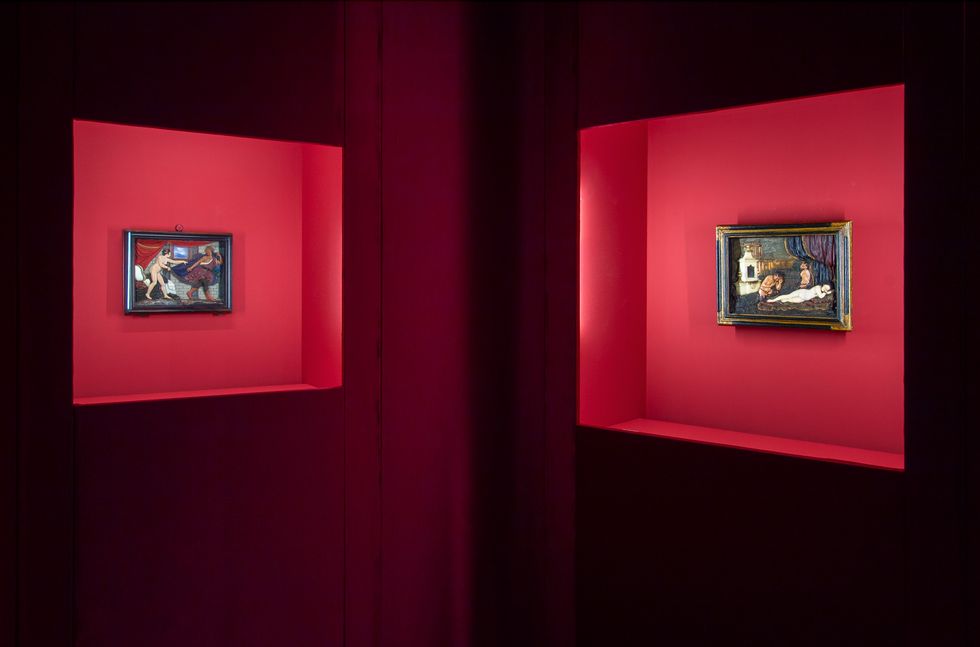two paintings displayed in illuminated red niches