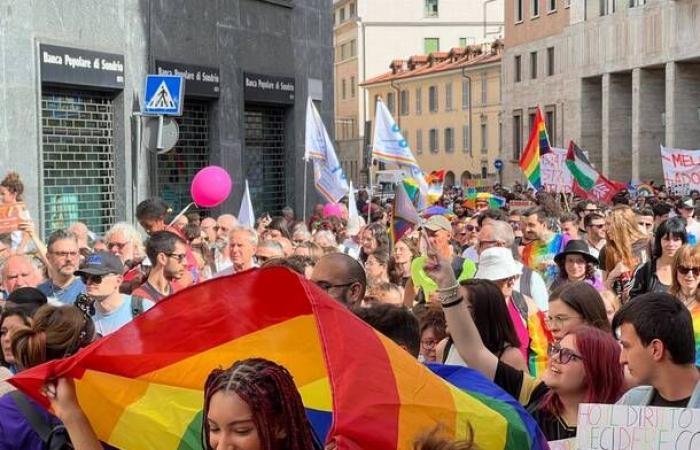 A colorful river of people parades through the city, many of them at Varese Pride